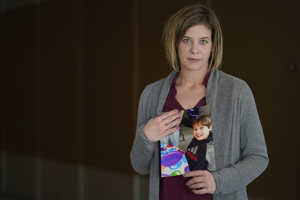 Kara Trainor poses for a picture with a photo of her son, Riley, 11, after making a statement during a hearing in New York, Thursday. Victims of opioids and those who have lost loved ones to the addiction crisis are unleashing their emotions on members of the family they blame for fueling the deadly epidemic.