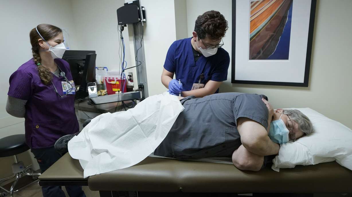 Ray Hoffman, right, who is immunocompromised, is given a shot of the two-shot dose of AstraZeneca’s Evusheld — the first set of antibodies grown in a lab to prevent COVID-19, Jan. 20, by Jose Lazaro, center, a medical assistant at a University of Washington Medicine clinic in Seattle as Cynde Wiederhold, left, a nurse, looks on.