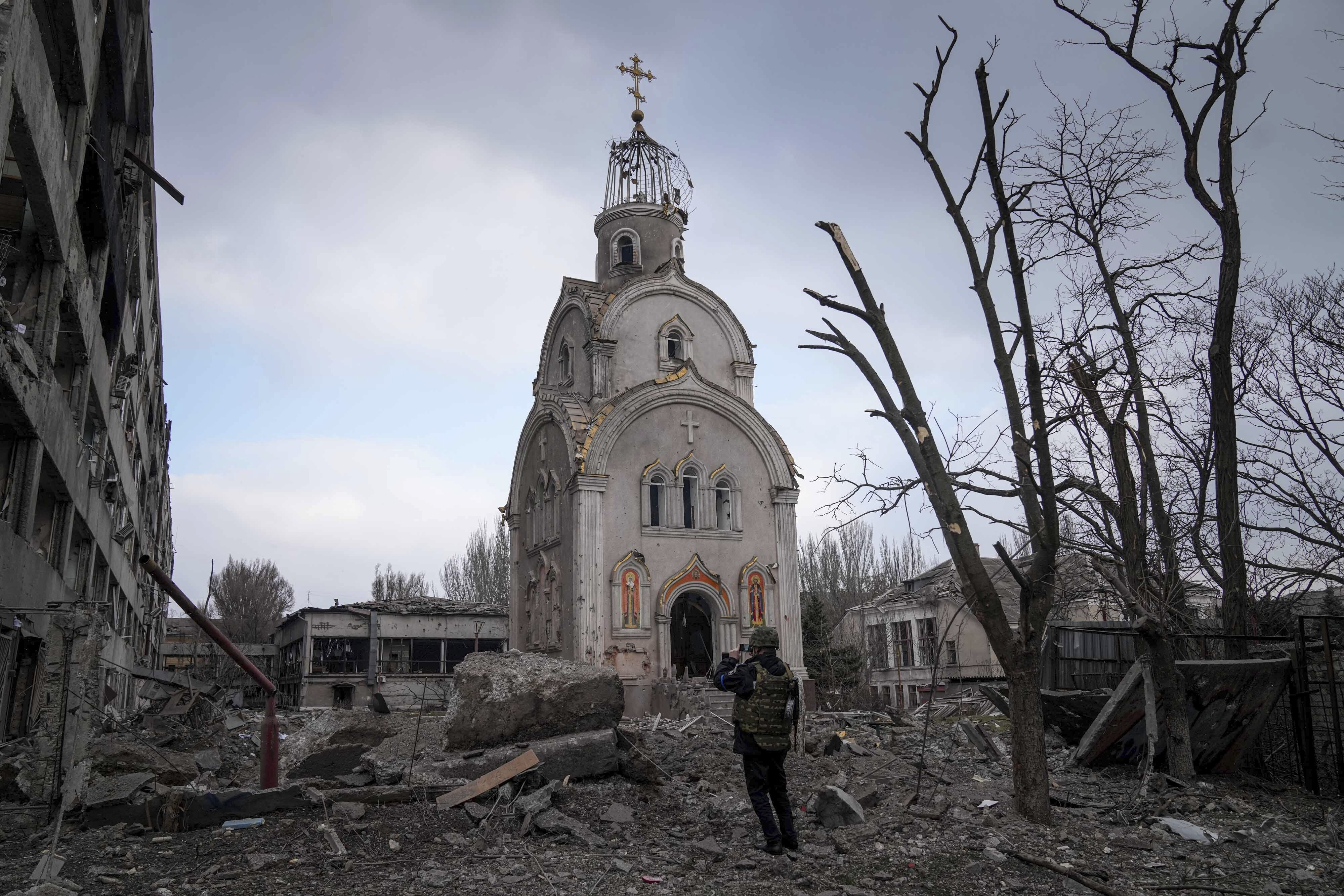 A Ukrainian serviceman takes a photograph of a damaged church after shelling in a residential district in Mariupol, Ukraine, Thursday.