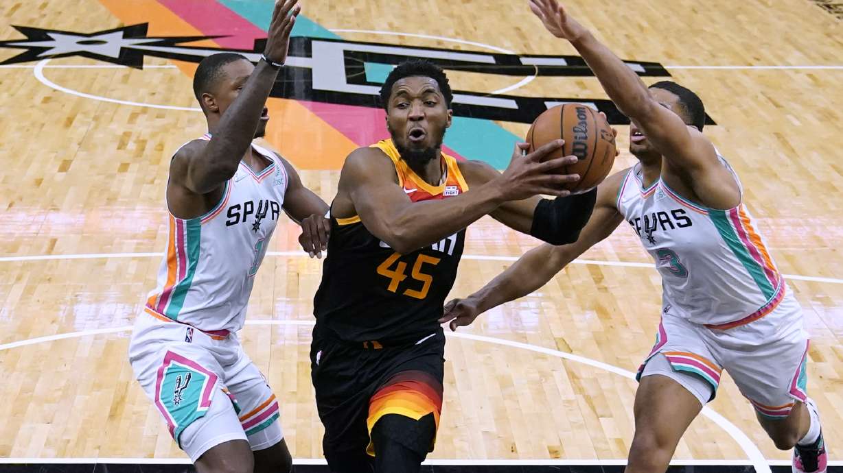 Utah Jazz guard Donovan Mitchell (45) drives to the basket between San Antonio Spurs guard Lonnie Walker IV (1) and forward Keldon Johnson (3) during the second half of an NBA basketball game Friday, March 11, 2022, in San Antonio.