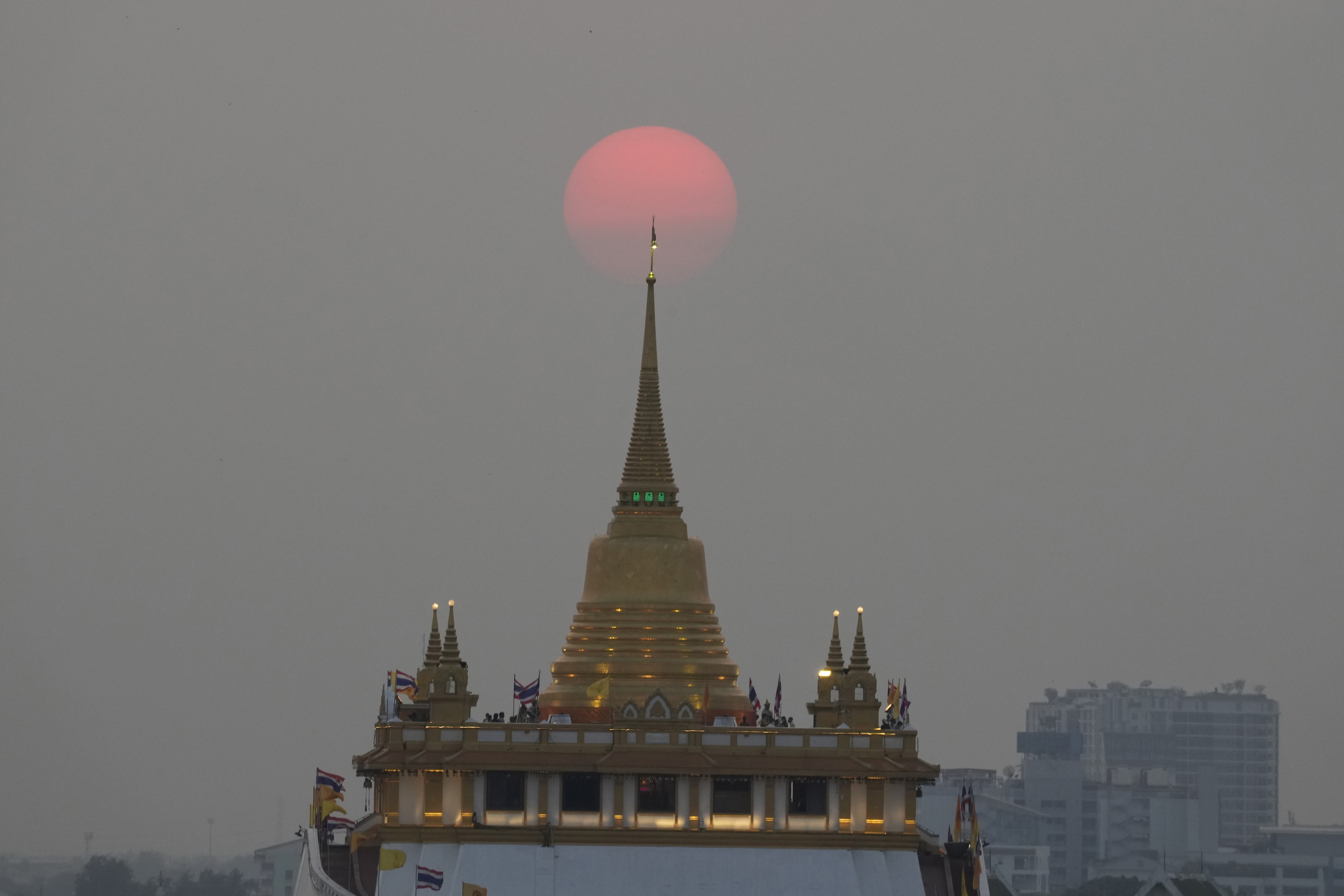 The sun sets behind the golden mount temple in Bangkok, Thailand, Saturday. Thousands of Russian tourists are stranded in Thailand's beach resorts because of the war in Ukraine, many unable to pay their bills or return home because of sanctions and canceled flights.