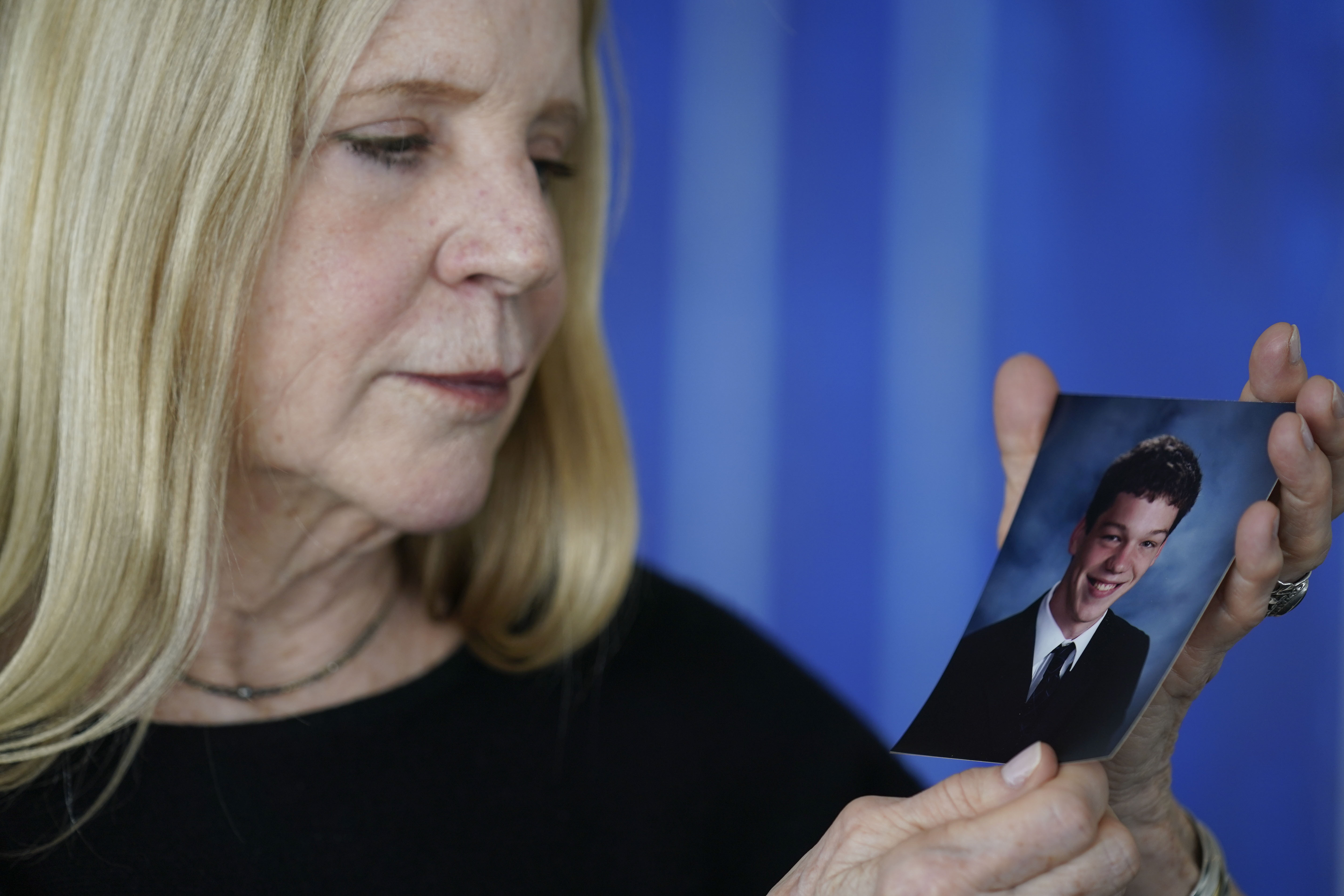 Dede Yoder poses for a picture with a photo of her son, Chris Yoder, after making a statement during a hearing in New York, Thursday. People who lost loved ones or years of their own lives to opioid addiction are getting their first and perhaps only chance to confront members of the Sackler family who own OxyContin maker Purdue Pharma. Thursday's virtual court hearing is being run by a U.S. Bankruptcy Court judge.