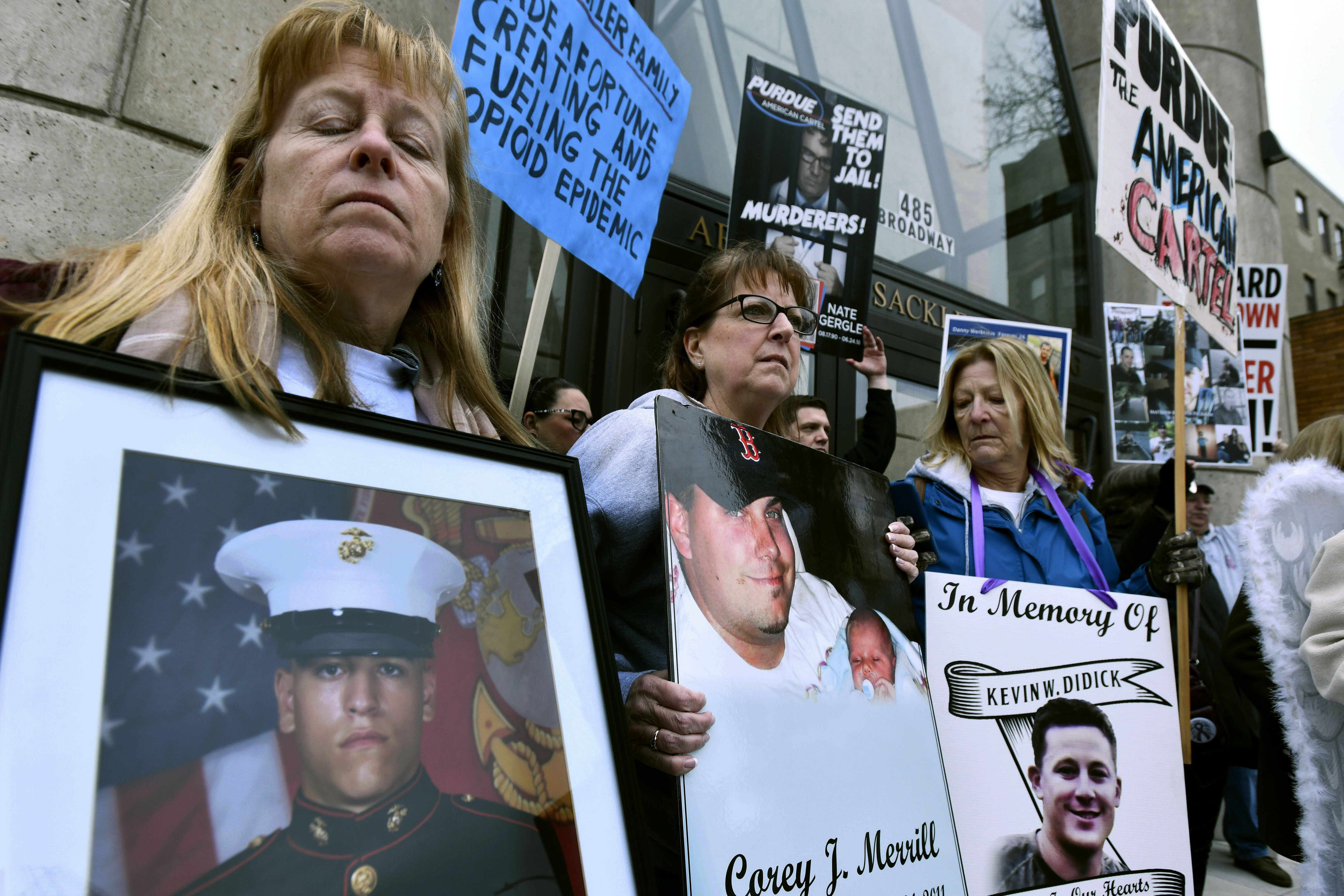 Kathleen Scarpone, left, of Kingston, N.H., and Cheryl Juaire, second from left, of Marlborough, Mass., protest in front of the Arthur M. Sackler Museum, at Harvard University, April 12, 2019, in Cambridge, Mass. Scarpone, who lost her son to OxyContin addiction, and Juarie addressed three Sackler family members during a virtual U.S. Bankruptcy Court hearing, Thursday.