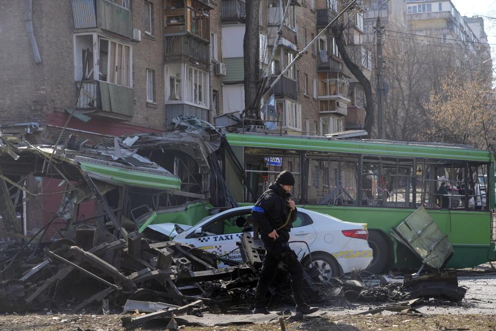 A Ukrainian soldier passes by a destroyed a trolleybus and taxi after a Russian bombing attack in Kyiv, Ukraine, Monday. Russia and Ukraine kept a fragile diplomatic path open with a new round of talks on Monday even as Moscow's forces pounded away at Kyiv and other cities across the country.