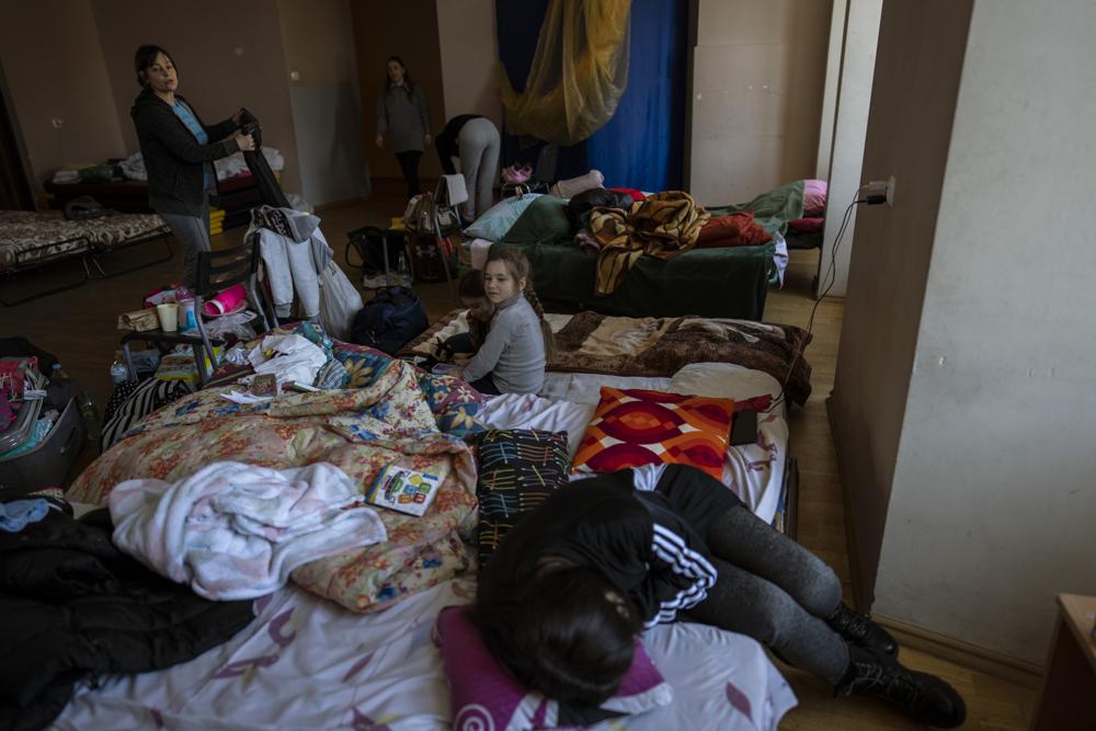 Families who fled the war in Ukraine stay inside a school in Przemysl, southeastern Poland, on Monday. Russia's military forces kept up their punishing campaign to capture Ukraine's capital with fighting and artillery fire in Kyiv's suburbs Monday after an airstrike on a military base near the Polish border brought the war dangerously close to NATO's doorstep.