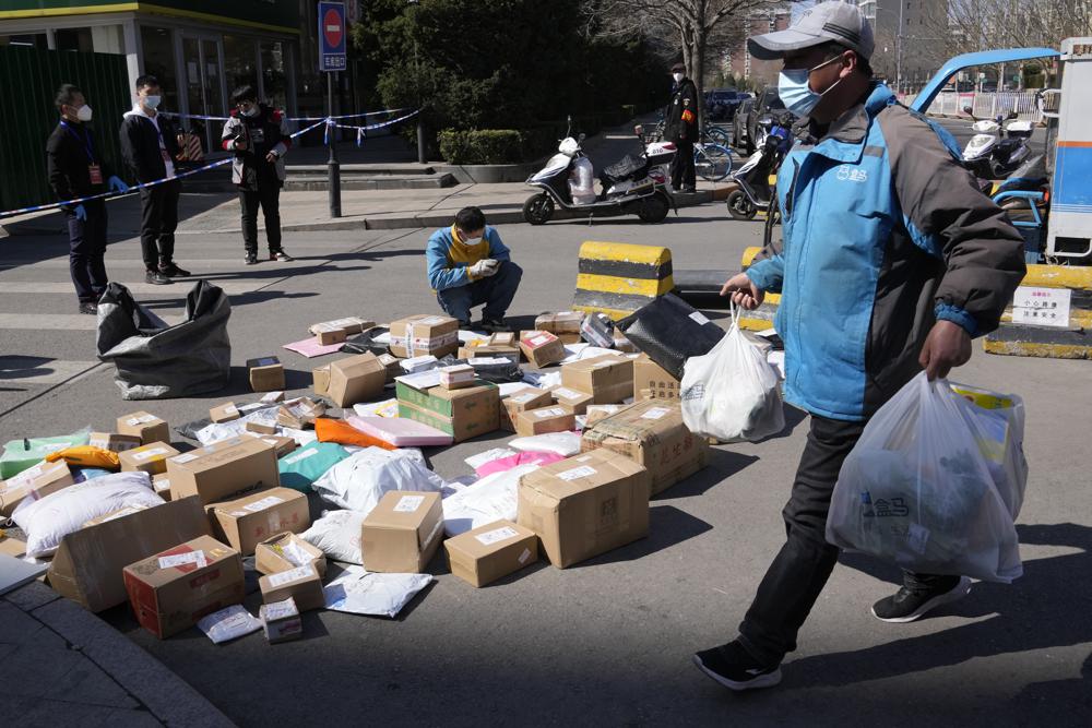 A delivery man sorts out parcels for delivery to a community under lock down after a case of coronavirus was detected, Monday in Beijing. Chinese authorities reported more than 1,300 locally transmitted cases of COVID-19 across dozens of mainland cities Monday as the fast-spreading variant commonly known as "stealth omicron" fuels China's biggest outbreak in two years.