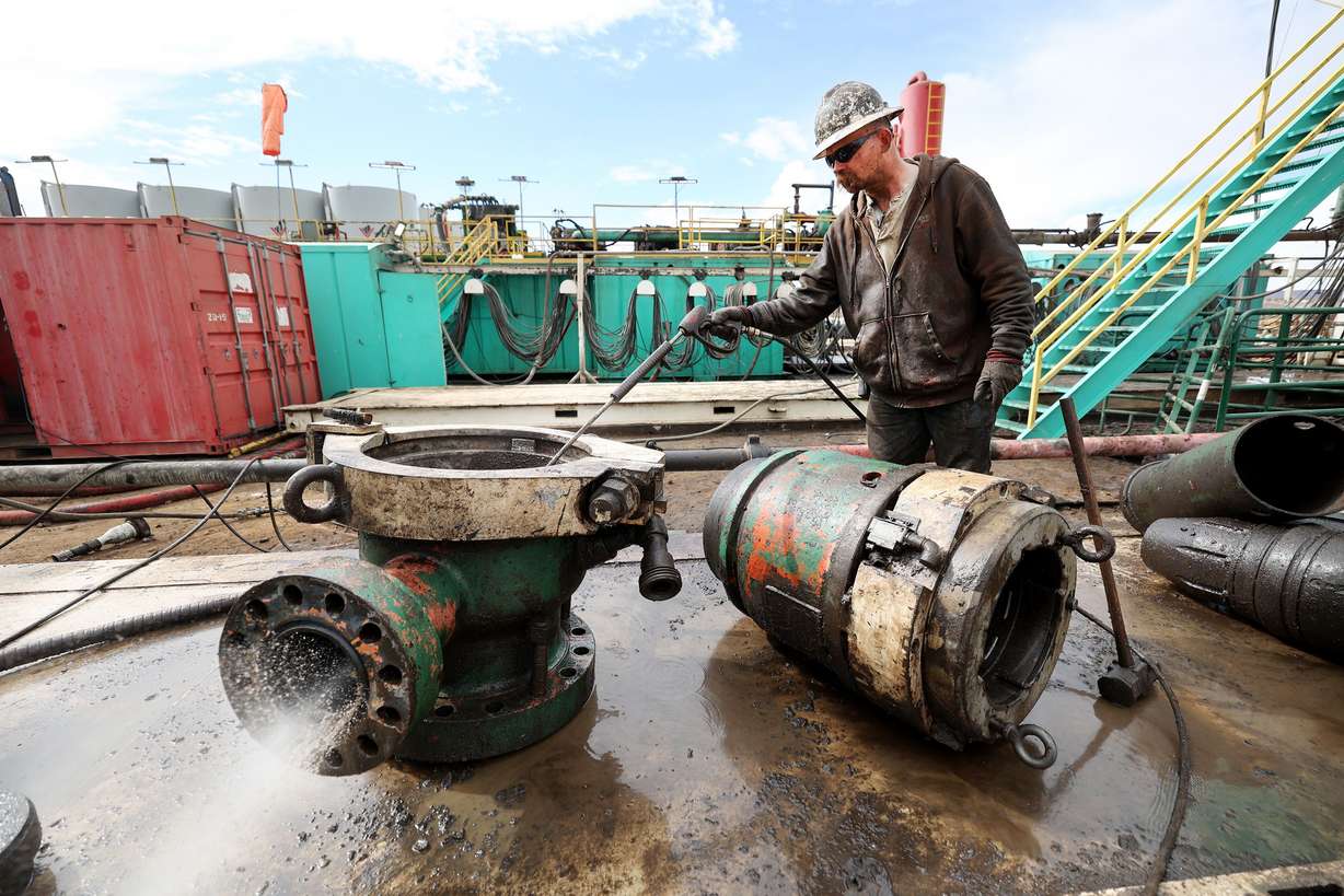 Jesse Keel uses high-pressure water to clean rig parts on an oil rig near Roosevelt on Sunday.
