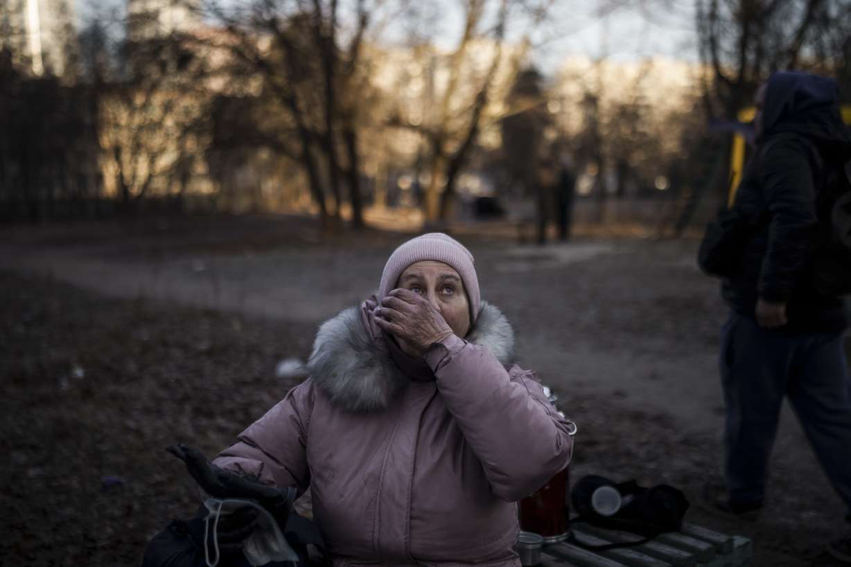 A woman reacts after being rescued by firefighters from her apartment in a burning building that was hit by artillery shells in Kyiv, Ukraine, Tuesday.