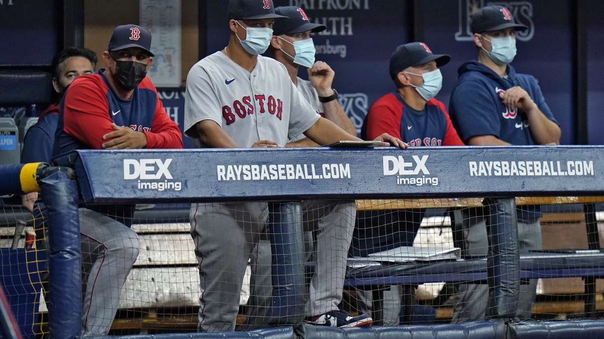 FILE - Boston Red Sox manager Alex Cora, left, and other members of the coaching staff wear protective masks during the fourth inning of a baseball game against the Tampa Bay Rays on Monday, Aug. 30, 2021, in St. Petersburg, Fla. Major League Baseball is dropping regular COVID-19 testing for all but symptomatic individuals while maintaining an abiity to move games if the public health situation in an area deteriorates. MLB and the players’ association finalized their 2022 COVID protocols on Tuesday, March 15, 2022, as it easing pandemic restrictions five days after reaching a collective bargaining agreement.