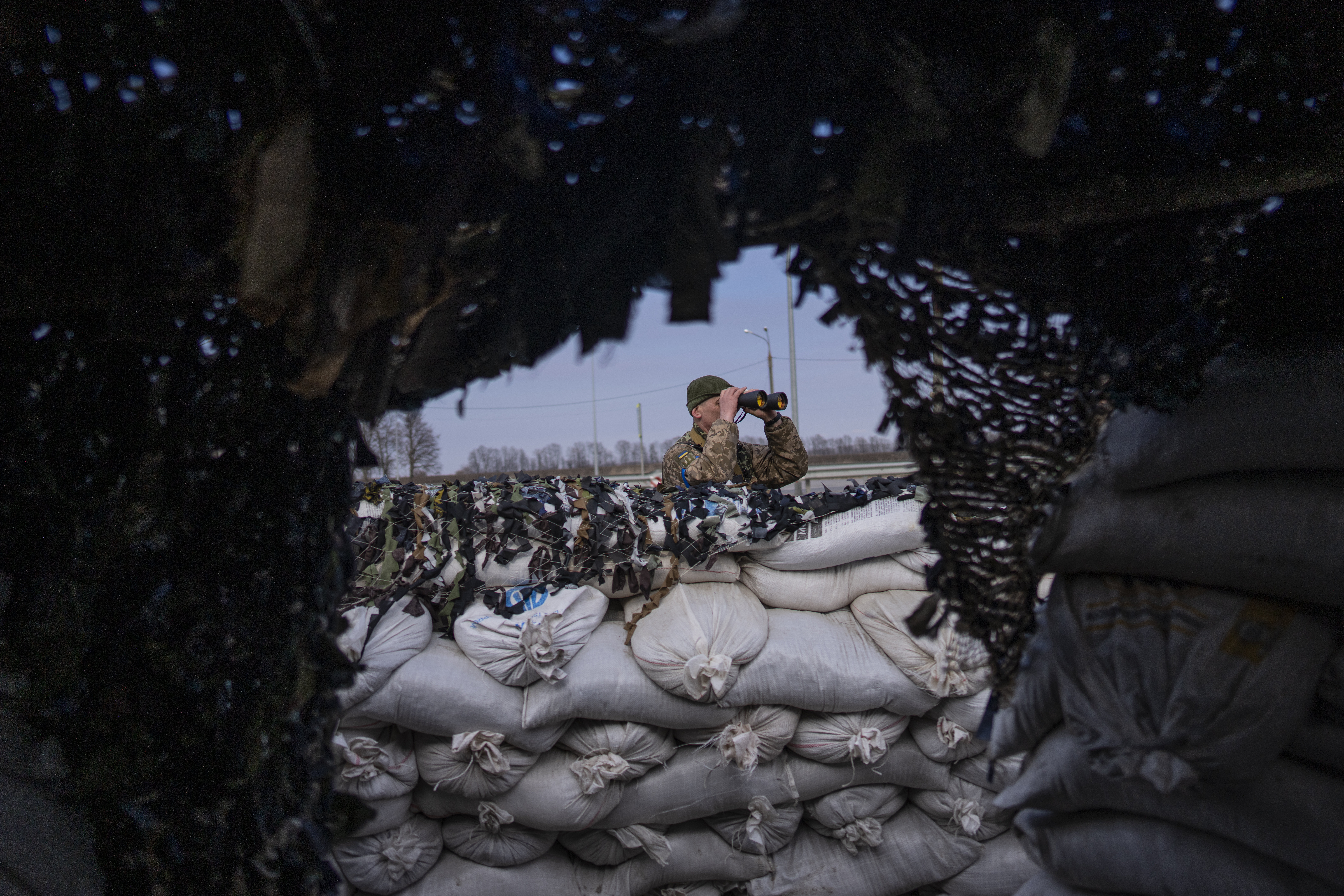 A Ukrainian soldier looks through binoculars at a military check point, in Lityn, Ukraine, Wednesday.
