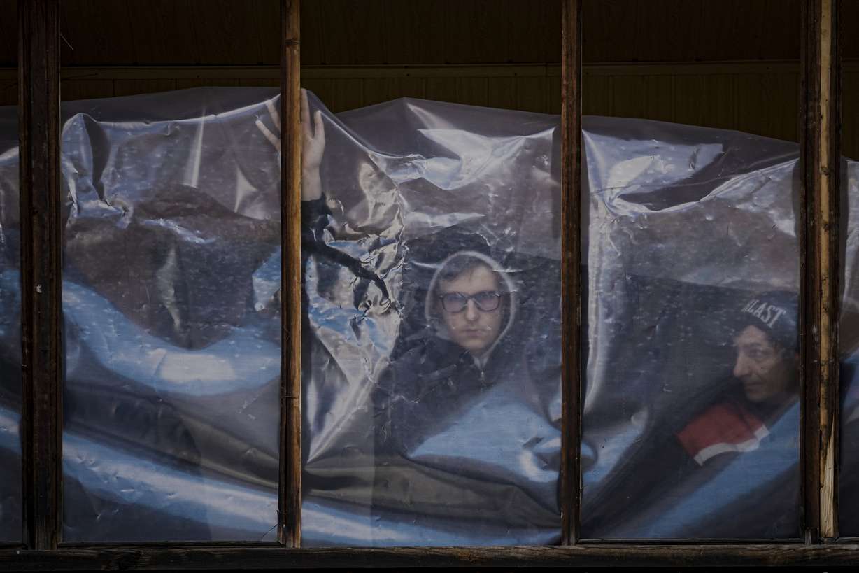 People put up plastic sheets to cover the broken windows of their apartments after parts of a Russian missile, shot down by Ukrainian air defense, landed on an apartment block, according to authorities, in Kyiv, Ukraine, Thursday.