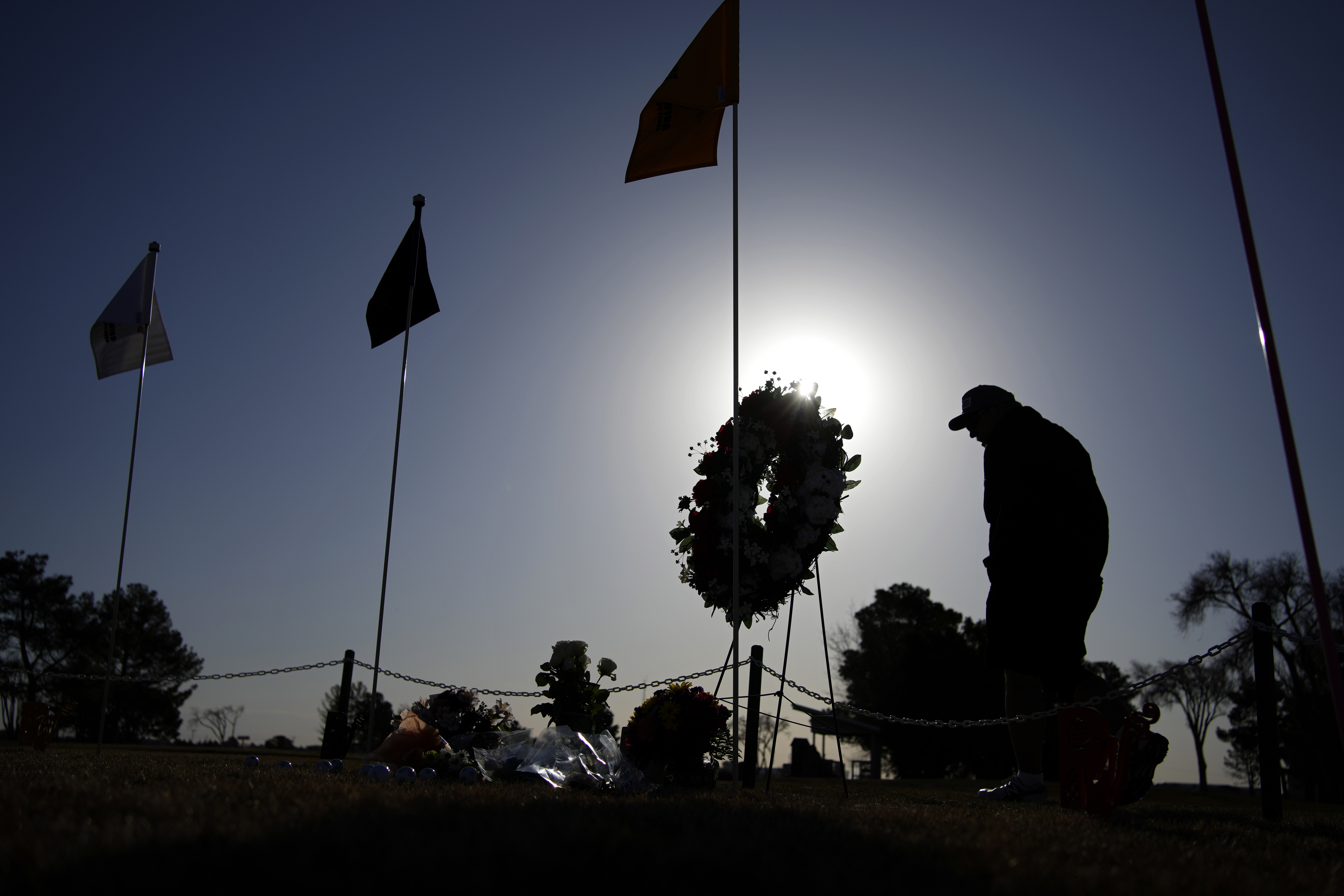 A golfer visits a makeshift memorial at the Rockwind Community Links Thursday, in Hobbs, New Mexico. The memorial was for student golfers and the coach of University of the Southwest killed in a crash in Texas.