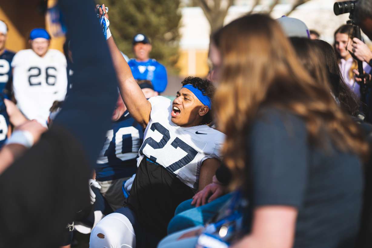 BYU defensive back Tavita Gagnier, center, pulls shirts, jerseys, hats and tickets out of a "swag" bag for the family of 9-year-old Logan Gagnier, his cousin who recently died unexpected at his home in Eagle Mountain, following practice, Thursday, March 17, 2022 in Provo.
