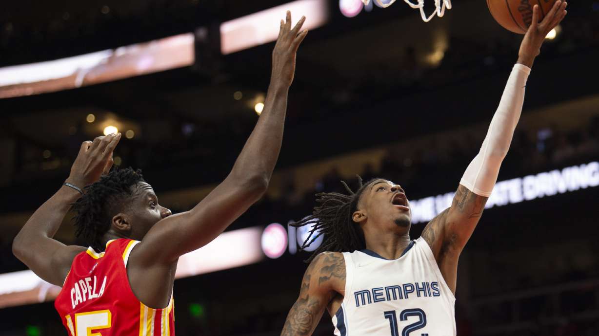 Memphis Grizzlies guard Ja Morant (12) scores past Atlanta Hawks center Clint Capela (15) during the first half of an NBA basketball game Friday, March 18, 2022, in Atlanta.