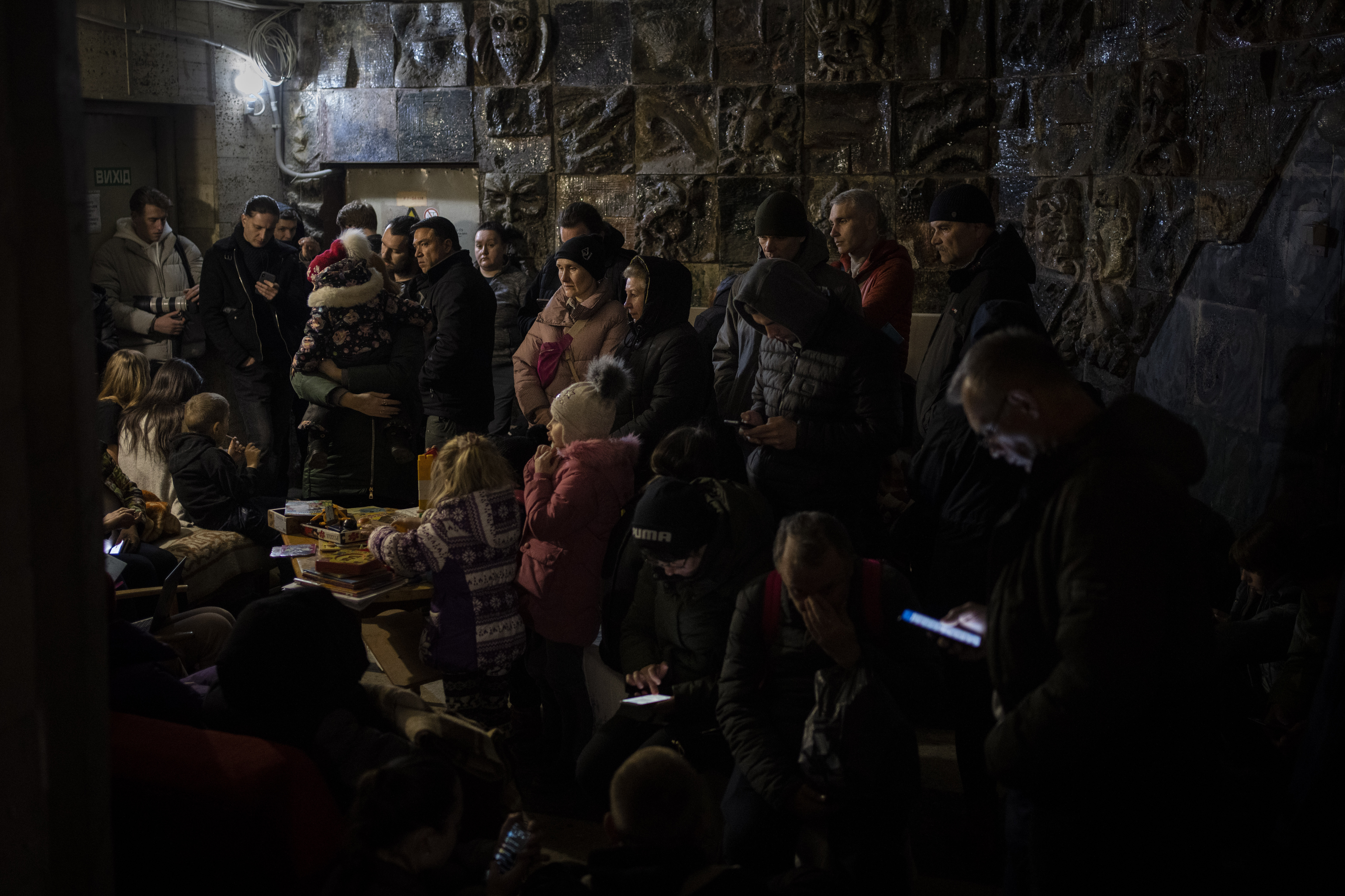 People gather in a basement, used as a bomb shelter, during an air raid in Lviv, Western Ukraine, Saturday. Lviv has been a refuge since the war began nearly a month ago, the last outpost before Poland and host to hundreds of thousands of Ukrainians streaming through or staying on.