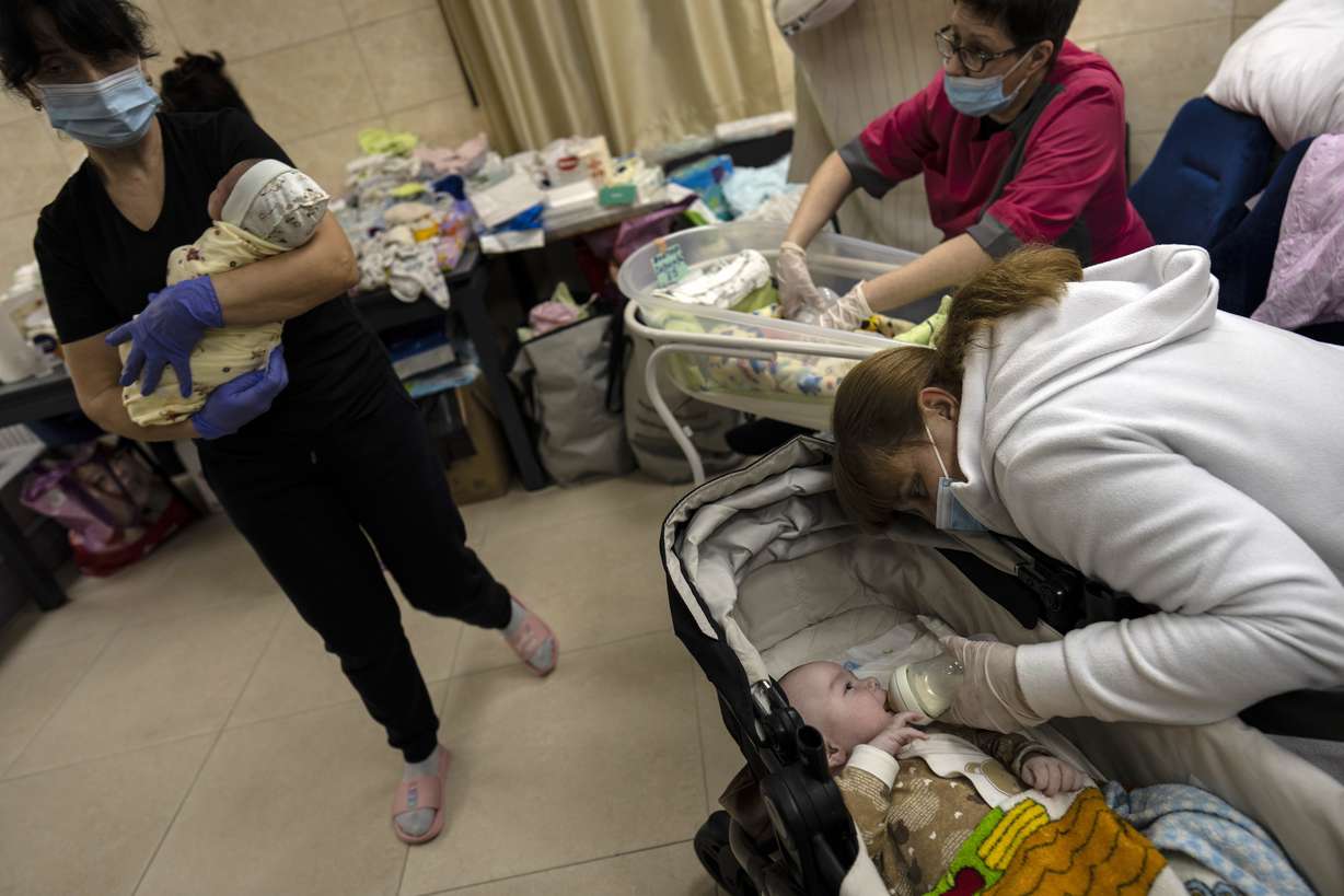 A worker feeds a newborn baby in a basement converted into a nursery in Kyiv, Ukraine, Saturday. Nineteen surrogated babies were born to surrogate mothers, with their biological parents still outside the country due to the war against Russia.