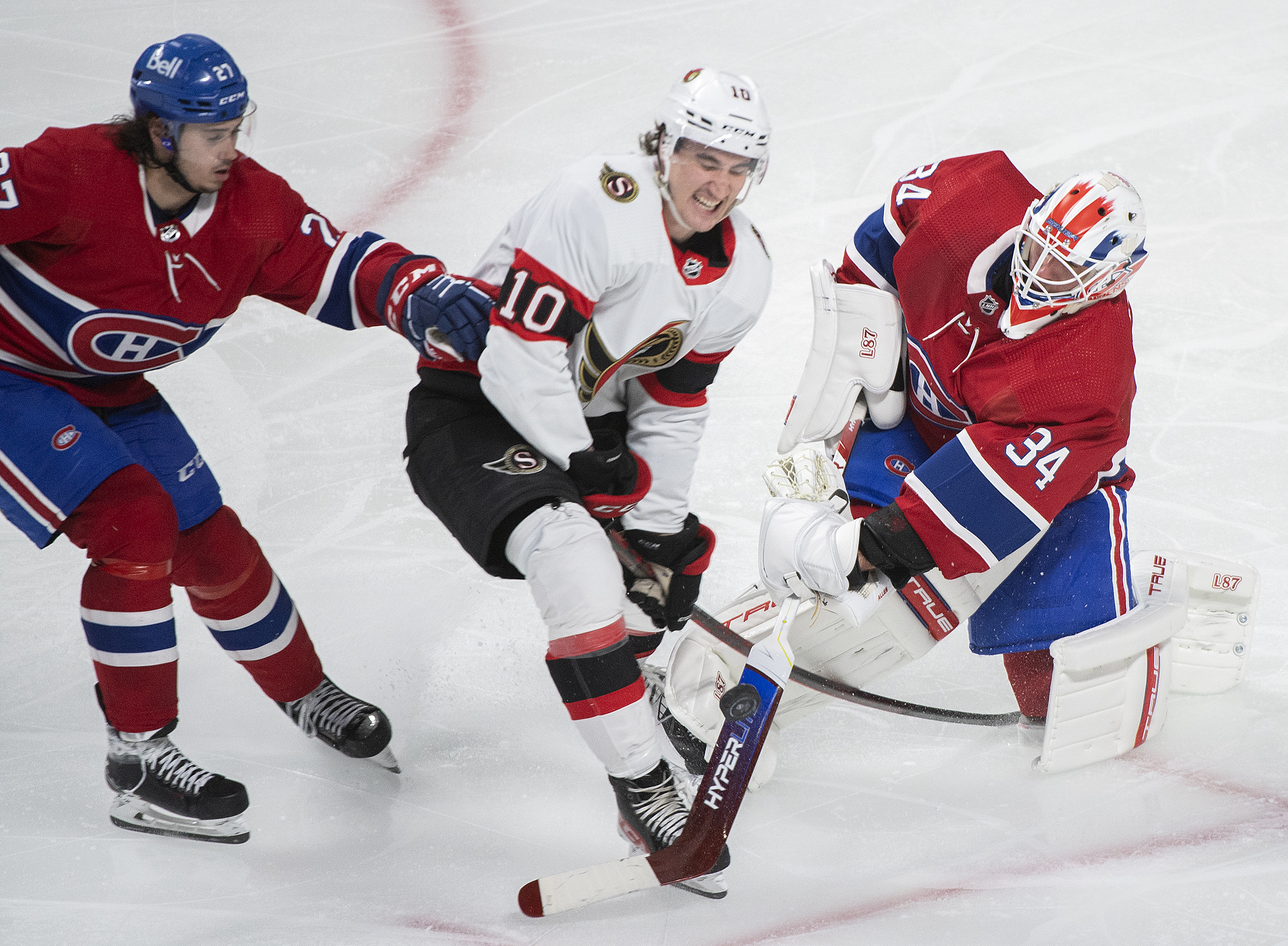 Montreal Canadiens goaltender Jake Allen clears the puck as Ottawa Senators' Alex Formenton (10) and Canadiens' Alexander Romanov (27) move in during the third period of an NHL hockey game Saturday, March 19, 2022, in Montreal. 