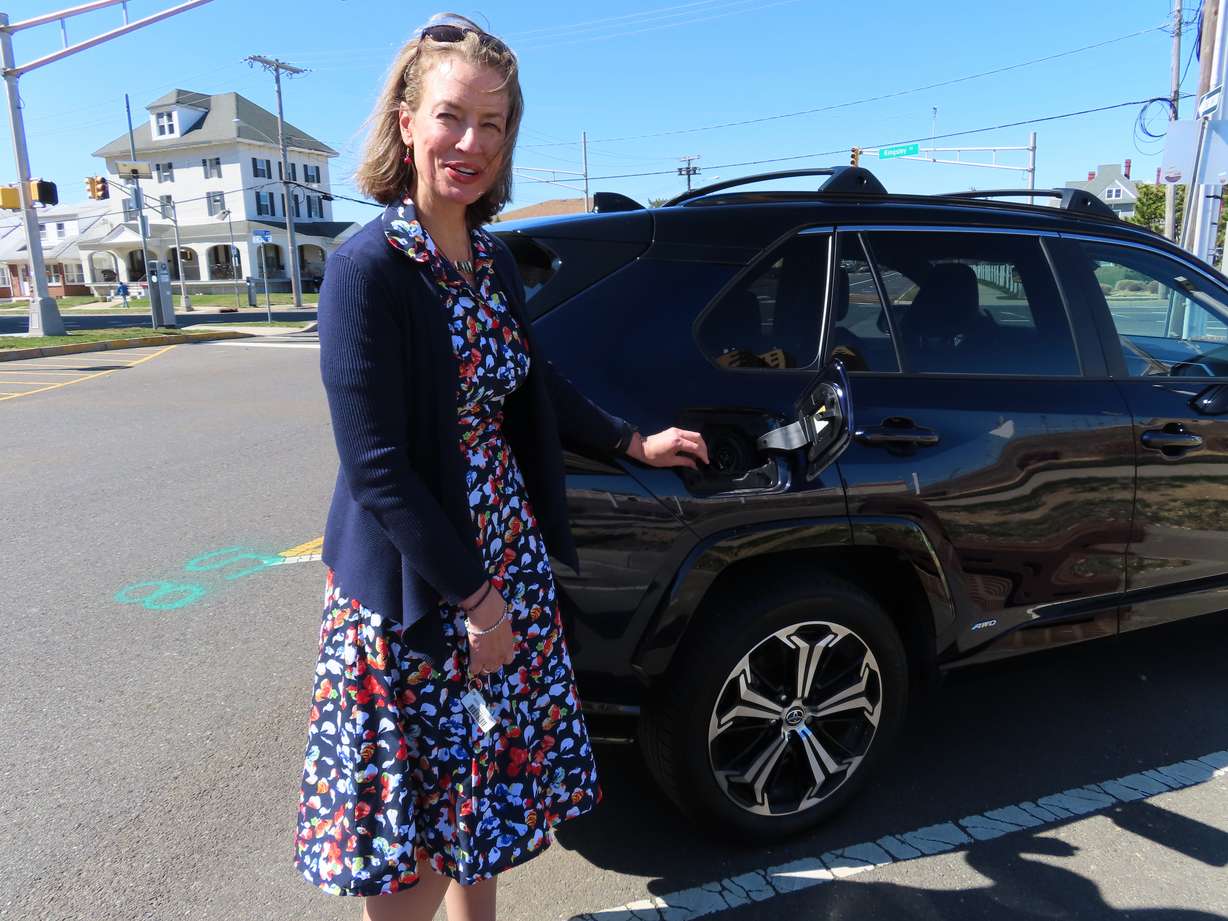 Kelly Mooij, an official with the New Jersey Board of Public Utilities, opens the charging port of an electric vehicle on Monday in Asbury Park, N.J. A nearby charging station was not yet operational.