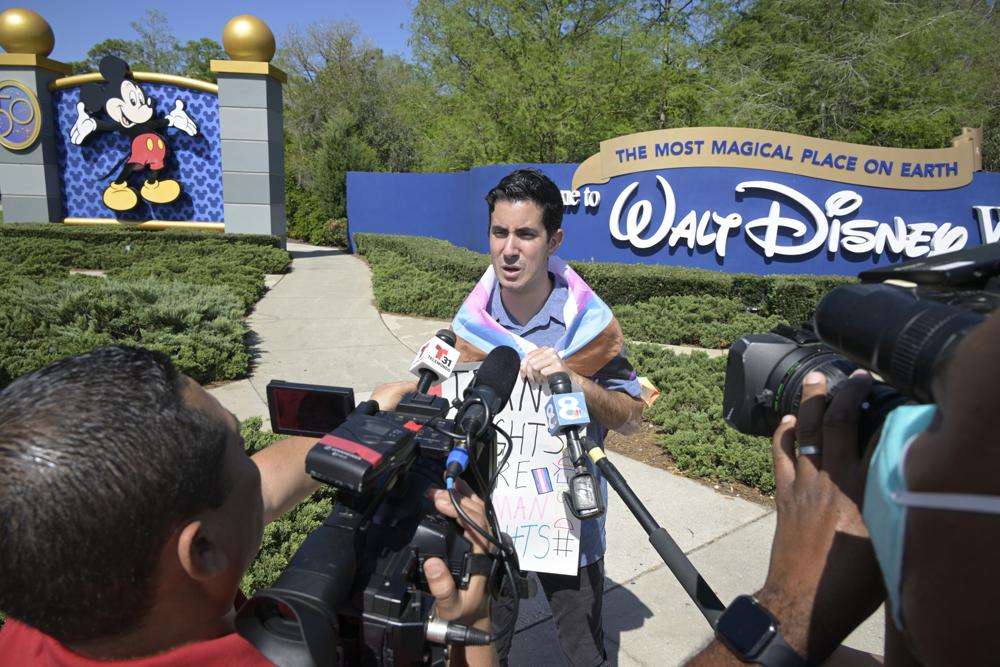 Disney cast member Nicholas Maldonado talks to reporters while protesting his company's stance on LGBTQ issues and participating in an employee walkout at Walt Disney World, Tuesday, in Lake Buena Vista, Fla.