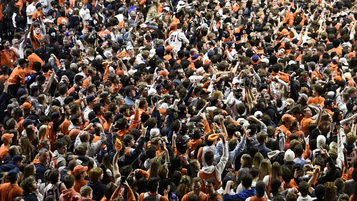 Fans storm the court at the conclusion of a college basketball game in Champaign, Ill., on Sunday, March 6. After about two months of falling COVID-19 cases, pandemic restrictions have been lifted across the U.S., and many people are taking off their masks and returning to indoor spaces.
