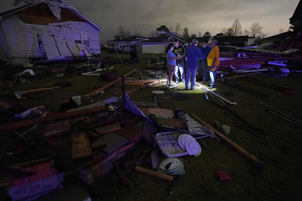 Christine Wiecek, left, and her husband Robert Patchus, second left, talk to neighbors amongst debris of their damaged homes after a tornado struck the area in Arabi, La., Tuesday.