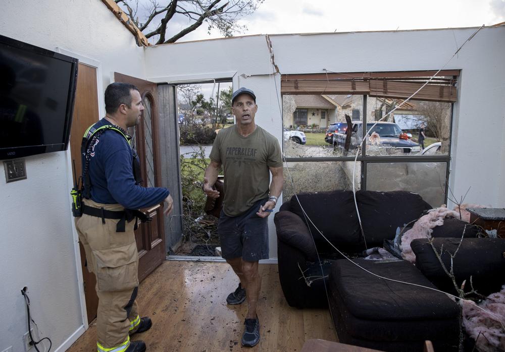 Michael Talamantez talks to a firefighter in his house on Stratford Drive in Round Rock, Texas, after it was destroyed by a tornado while he was inside on Monday.