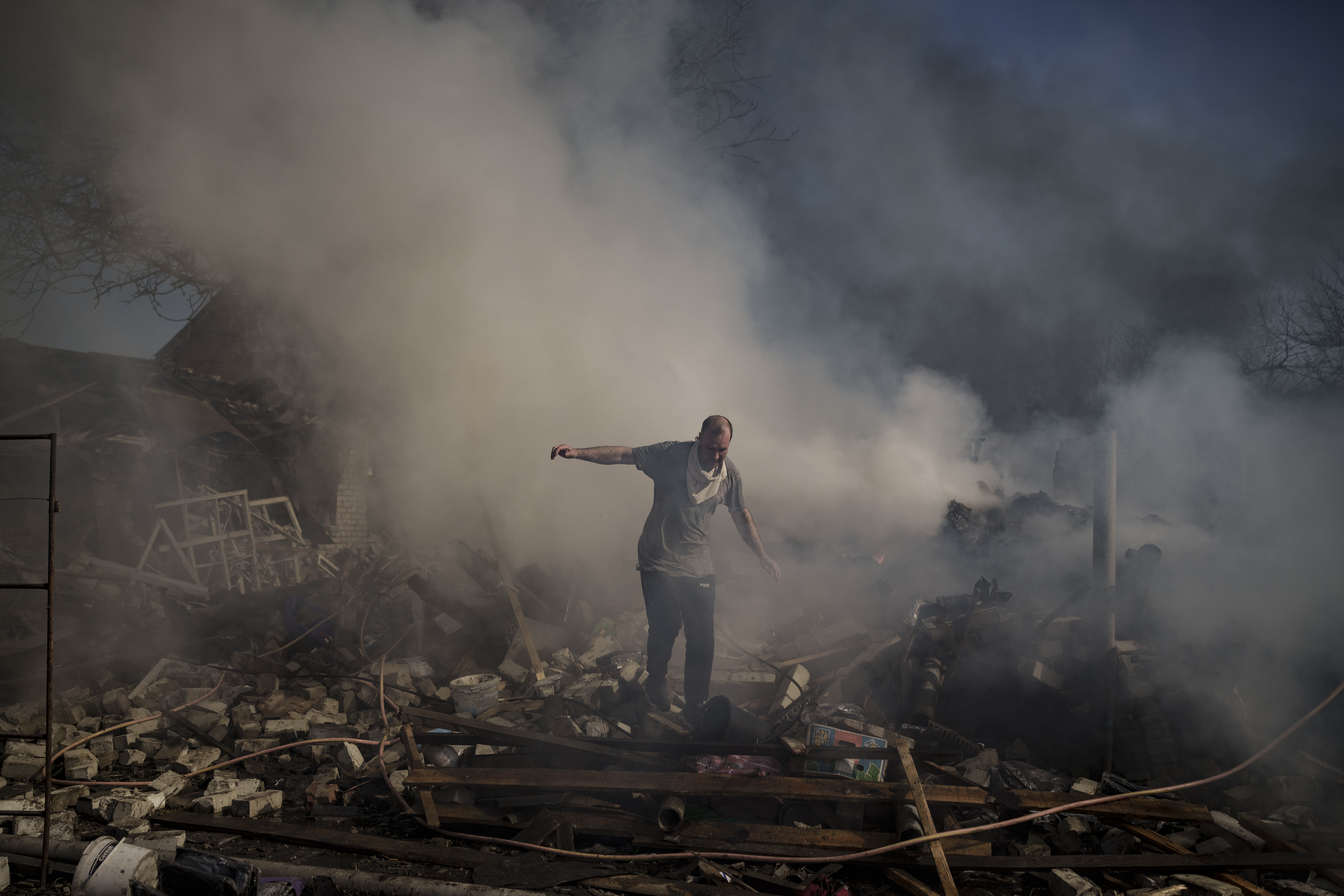 A man walks on the debris of a burning house, destroyed after a Russian attack in Kharkiv, Ukraine, Thursday. About 300 people were killed in the Russian airstrike last week that blasted open a Mariupol theater, Ukrainian authorities said Friday, in what would make it the war’s deadliest known attack on civilians yet.