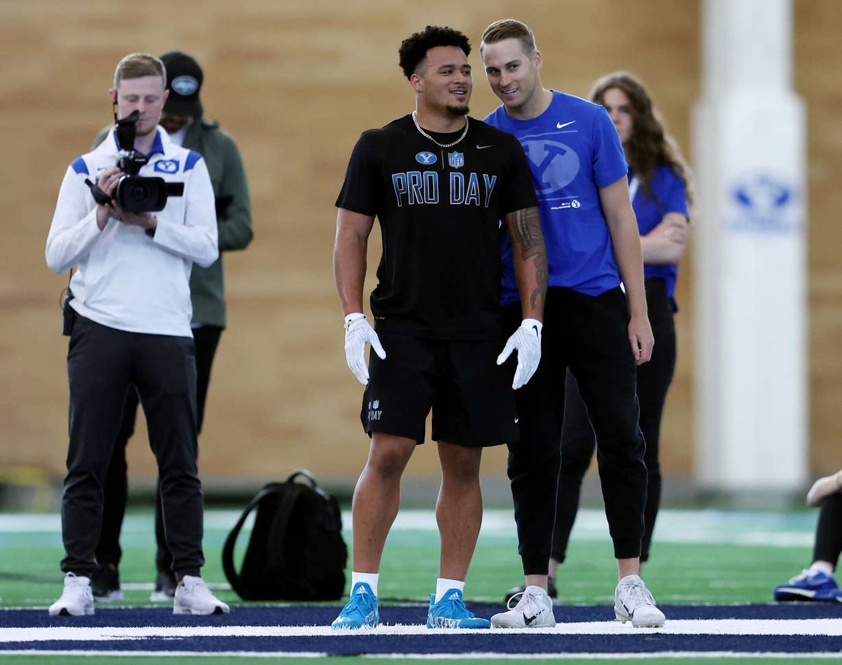 BYU running back Tyler Allgeier, center, talks with quarterback Baylor Romney during BYU's pro day at the university's indoor practice facility in Provo on Friday, March 25, 2022.