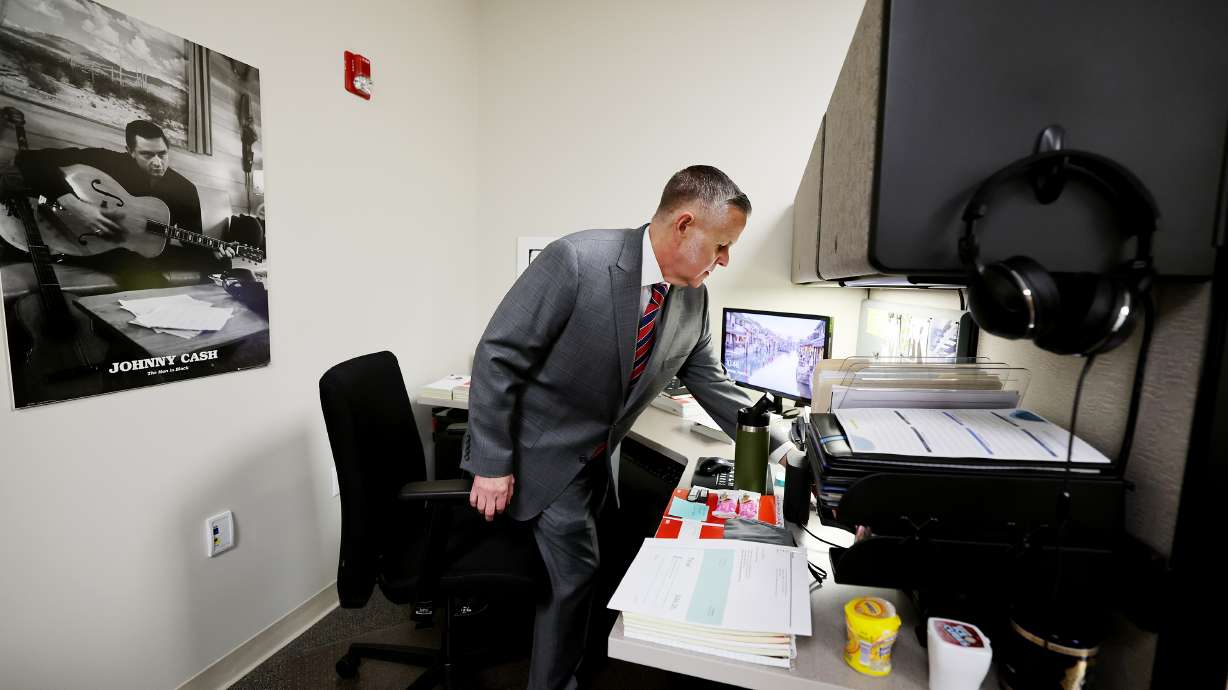 Unified Police detective Ben Pender, who is assigned to the cold case unit, adjusts his desk before posing for photos following an interview at the Salt Lake County Sheriff’s Office in South Salt Lake on Tuesday, March 22.