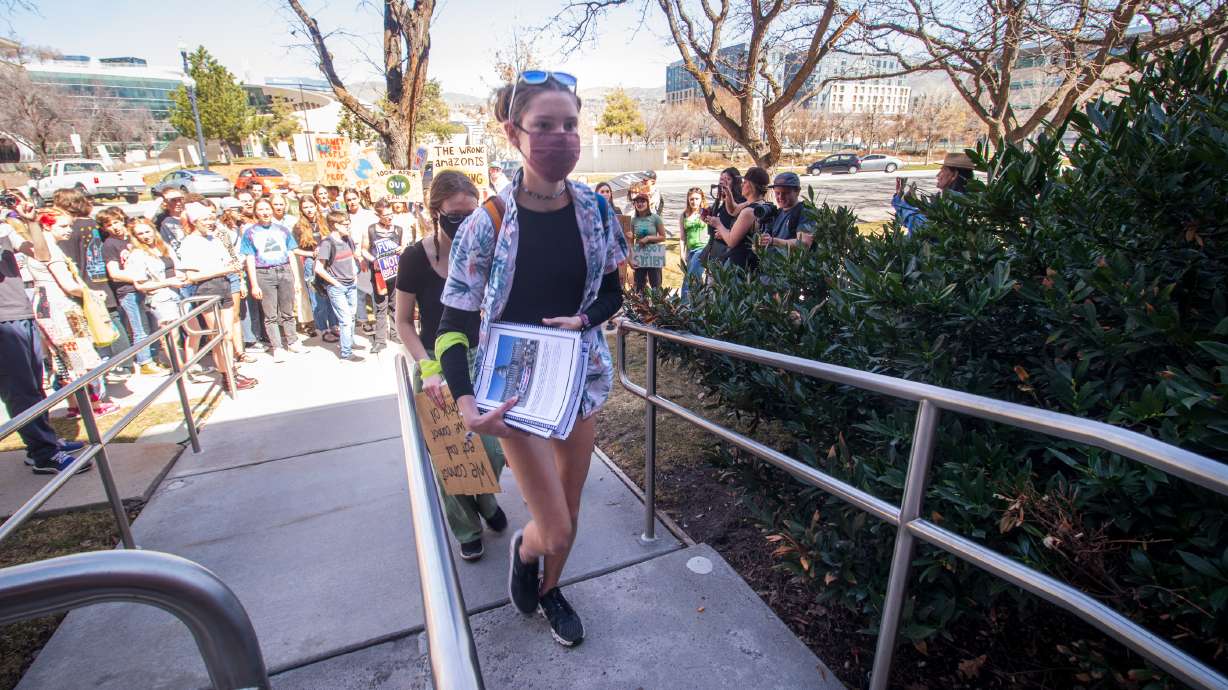 Natalie Roberts, a freshman at West High School, holds a stack of climate reports and a letter to state school board members as she leads Ava Curtis and Mandy Merrill, both seniors at Taylorsville High School, into the Utah State Board of Education building in Salt Lake City on Friday. The group represented students seeking for Utah to add more climate education.