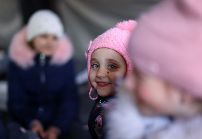 FILE PHOTO: Children of a family from Mykolaiv sit inside a tent to warm up after crossing the border from Ukraine to Poland, fleeing the Russian invasion of Ukraine, at the border checkpoint in Medyka, Poland, March 20, 2022.