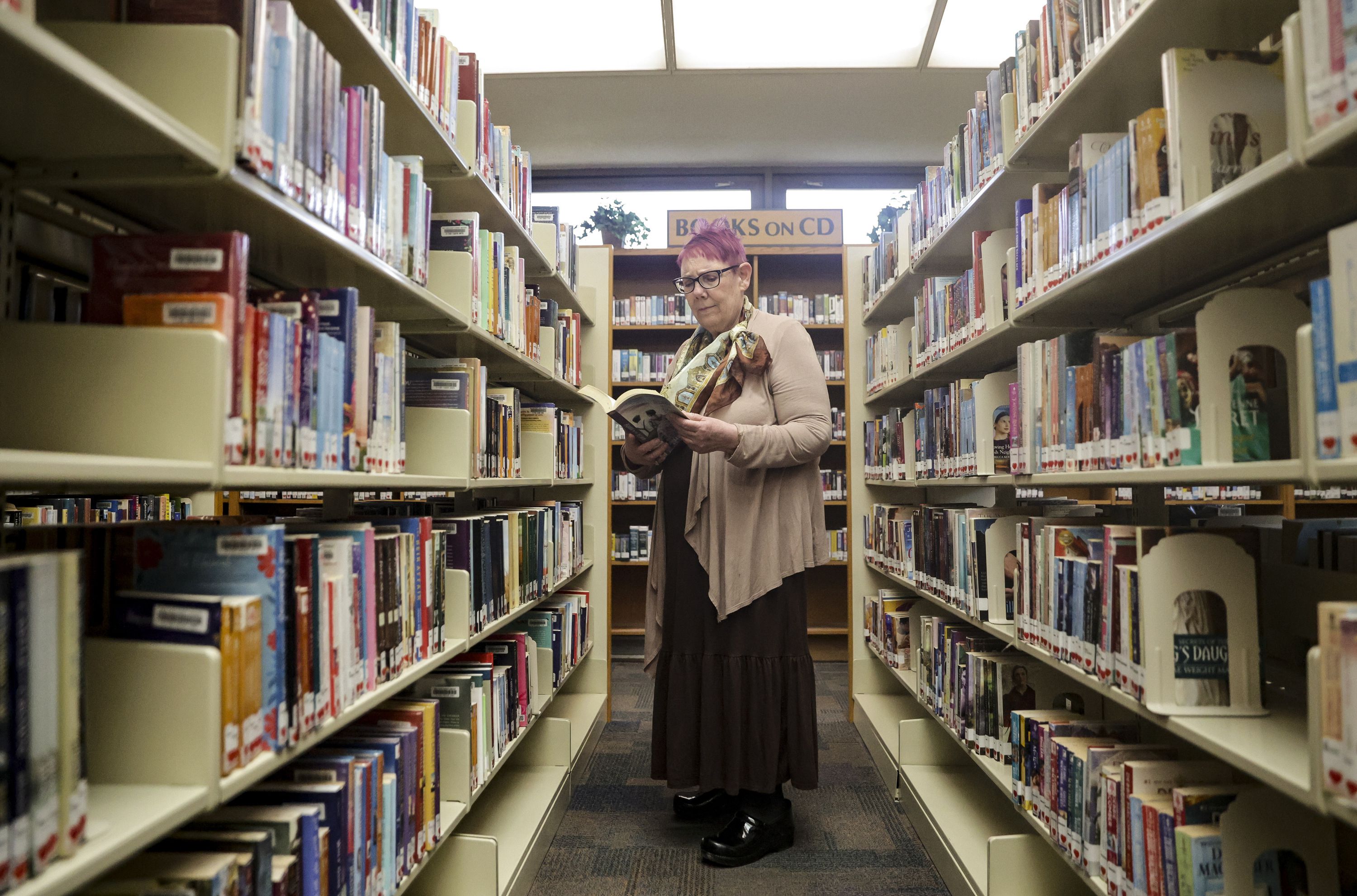 Wanda Mae Huffaker, a librarian with Salt Lake County Library for more than 40 years, flips through a book at the Ruth Vine Tyler Library in Midvale on Thursday. Huffaker has received more emails challenging the content of books during the past couple of years.