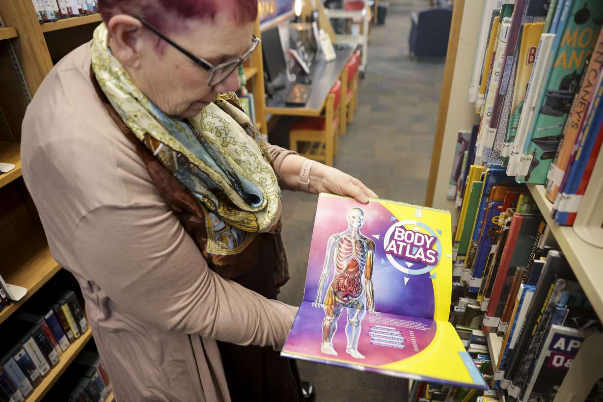 Wanda Mae Huffaker, a librarian at Ruth Vine Tyler Library in Midvale, flips through “Ultimate Body-pedia,” as books related to sex have often been targeted to be removed from library shelves, on Thursday.