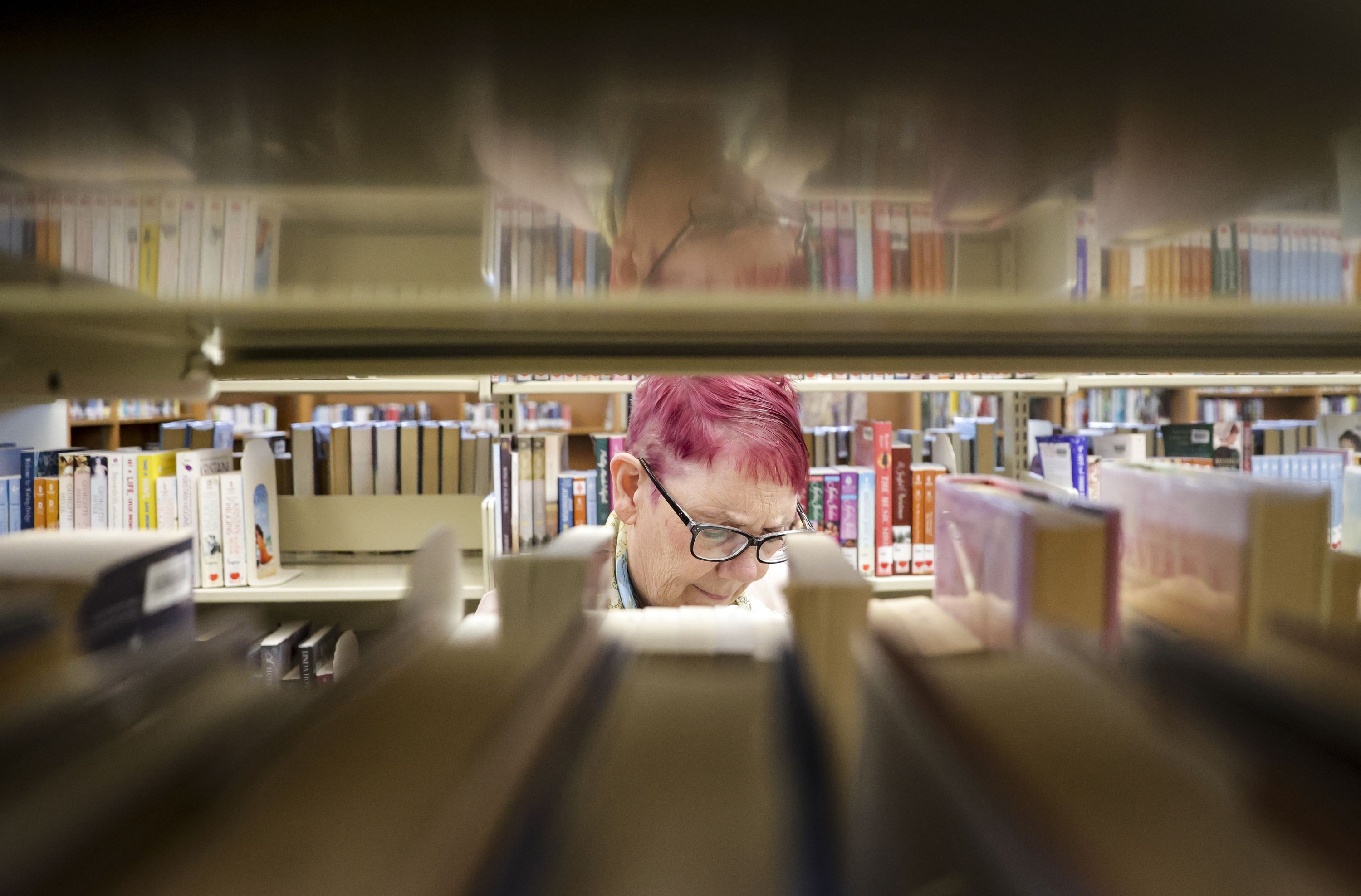 Wanda Mae Huffaker, a librarian with Salt Lake County Library for more than 40 years, flips through a book at the Ruth Vine Tyler Library in Midvale on Thursday. Huffaker has received more emails challenging the content of books during the past couple of years.