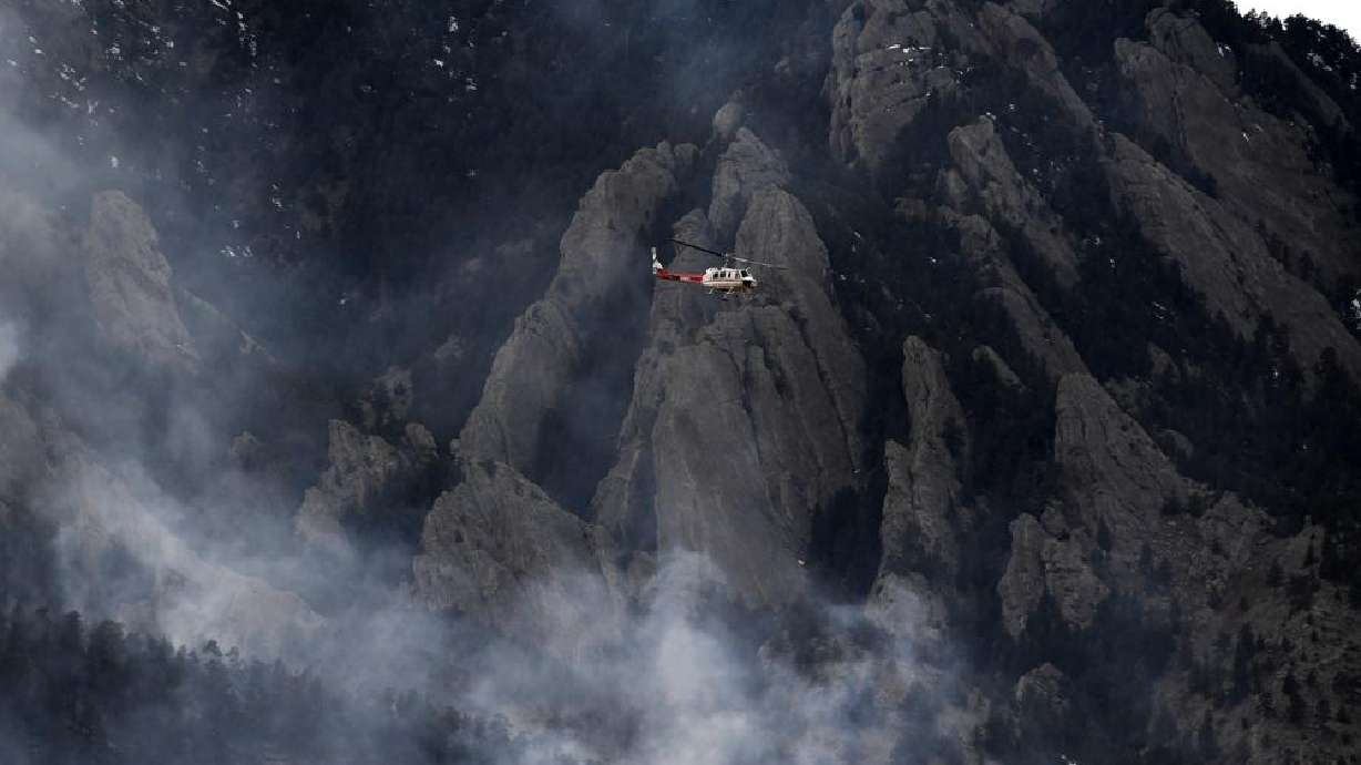 A helicopter flies above the smoke from the NCAR fire as it burns in the foothills south of the National Center for Atmospheric Research, Saturday in Boulder, Colo. The NCAR fire prompted evacuations in south Boulder and pre-evacuation warning for Eldorado Springs.