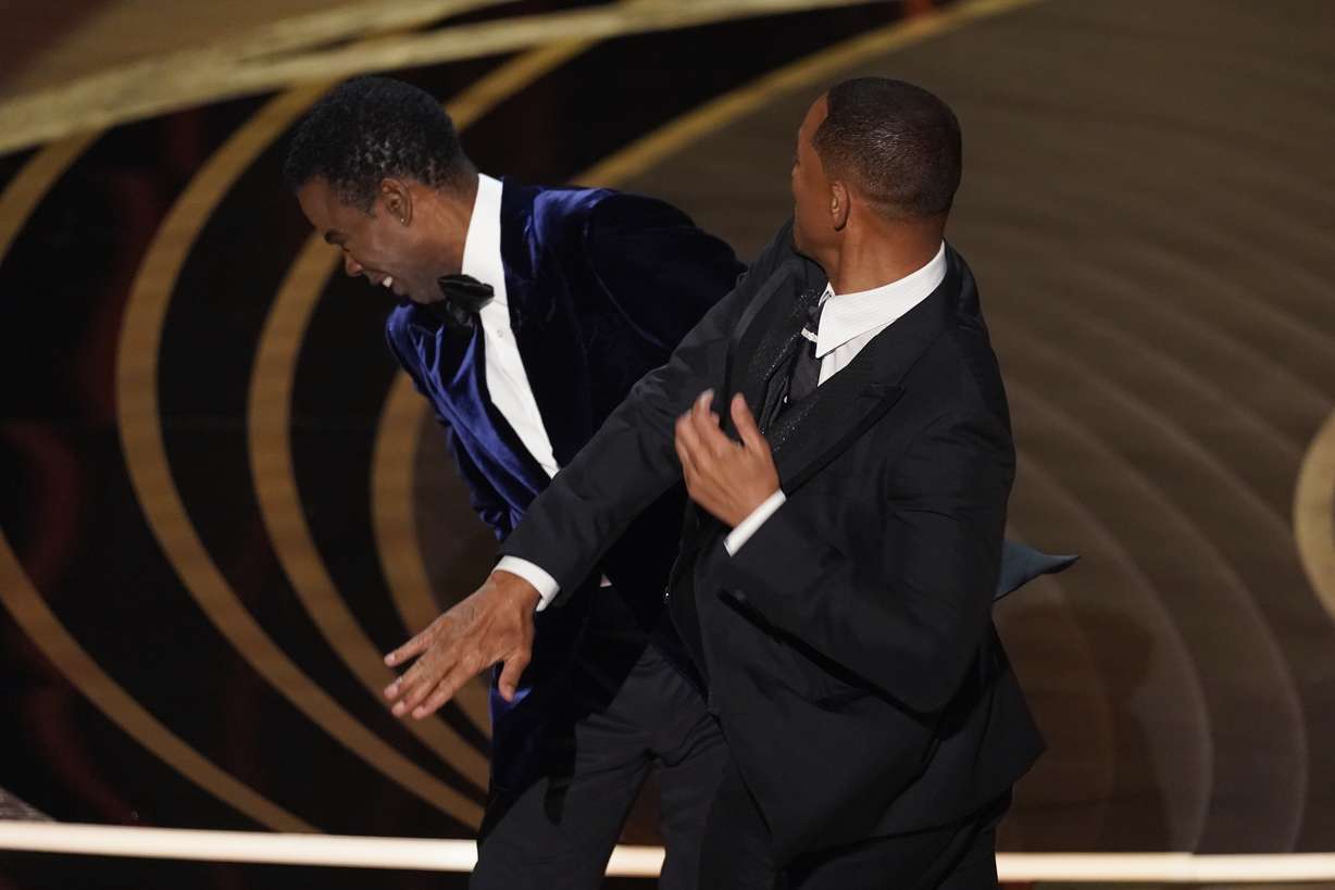 Will Smith, right, hits presenter Chris Rock on stage while presenting the award for best documentary feature at the Oscars on Sunday, at the Dolby Theatre in Los Angeles.