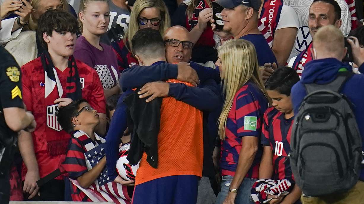 United States' Christian Pulisic, in orange top, is hugged by his father Mark Pulisic, center, after Christian Pulisic scored three goals in a FIFA World Cup qualifying soccer match against Panama, Sunday, March 27, 2022, in Orlando, Fla. The U.S. won 5-1.