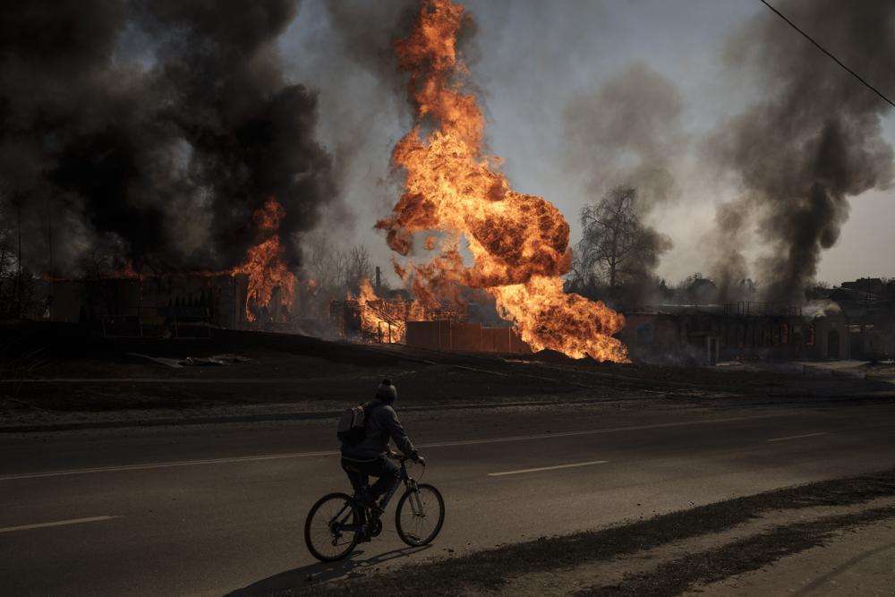 A man rides his bike past flames and smoke rising from a fire following a Russian attack in Kharkiv, Ukraine, on Friday.