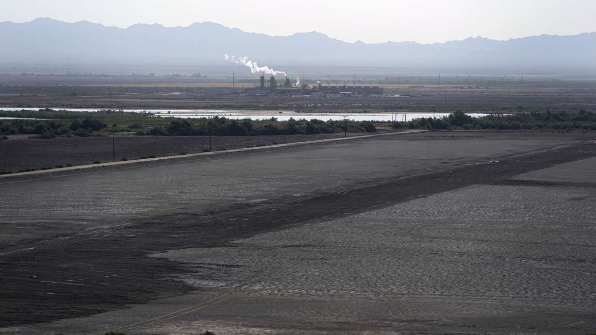 A dried up portion of the Salton Sea stretches out with a geothermal power plant in the distance in Niland, Calif., July 15, 2021. Demand for electric vehicles has shifted investments into high gear to extract lithium from geothermal wastewater around the rapidly shrinking body of water.