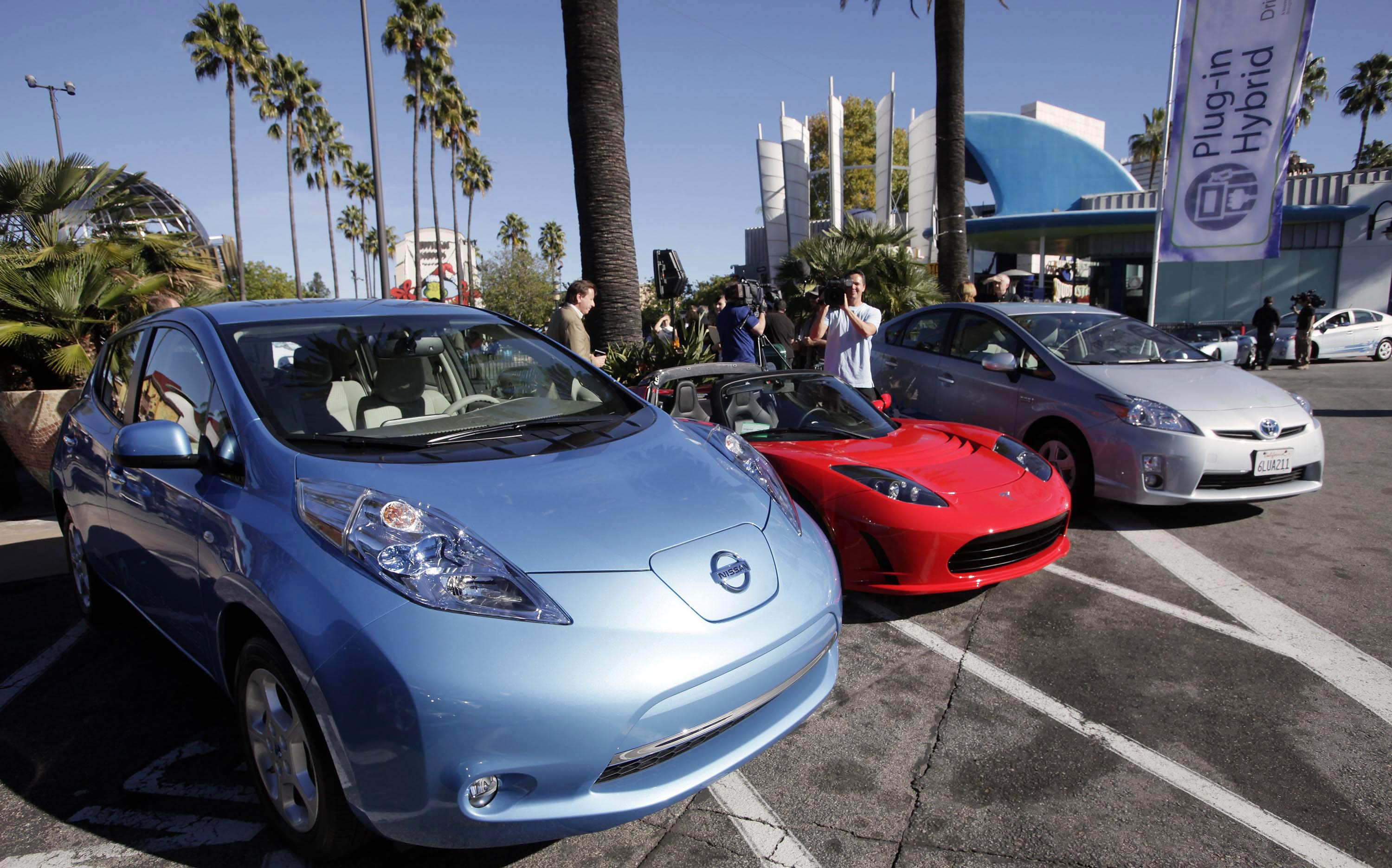 From left, electric cars from Nissan, Tesla, and Toyota are presented at a news conference in Los Angeles on Dec. 13, 2013.