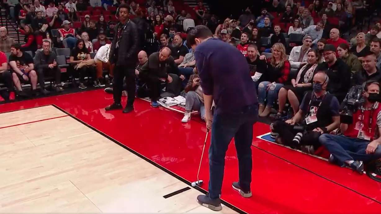 An NBA fan sets up for what would become a full-court hole-in-one putt on the Portland Trailblazers' home court at the Moda Center during a game on March 25.
