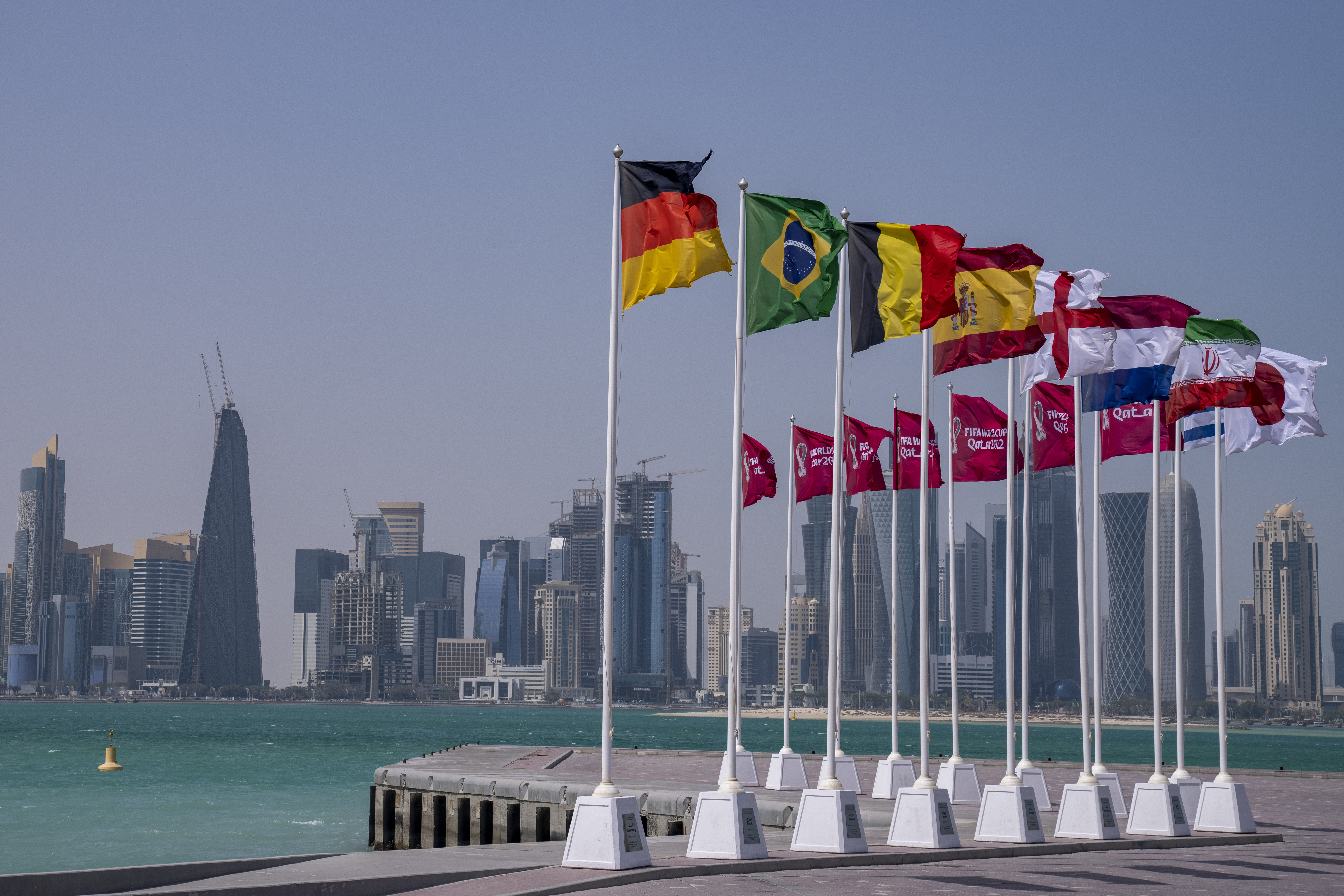 Flags of some of the qualified countries of the World Cup  wave at the seafront in Doha, Qatar, Tuesday, March 29, 2022. The draw for the World Cup will be held in Doha on April 1.