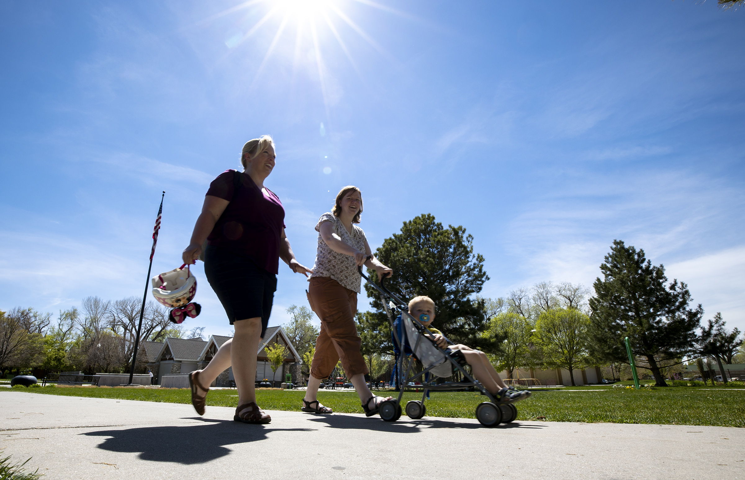 Stephanie Christensen talks with friend Katie Hyatt and her son, David Hyatt, as they enjoy the warm weather while taking a walk in Liberty Park in Salt Lake City on April 30, 2021. Liberty Park will serve as one of four bases for a new city park ranger program launching later this year.