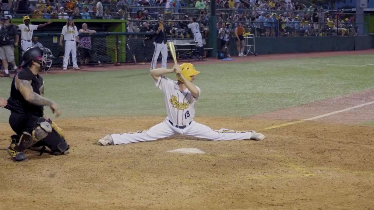 A batter for the Savannah Bananas baseball team does the splits as he waits for the opposing team to pitch the ball.