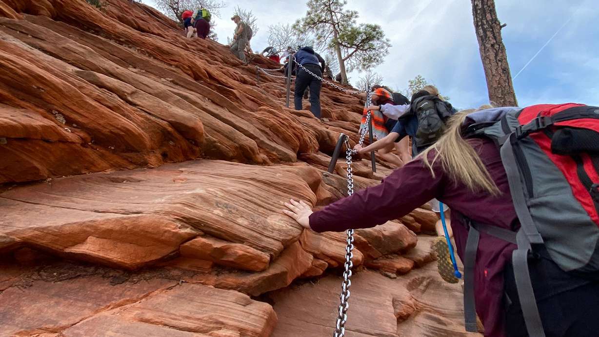 Hikers climb up the chained section of the hike to Angels Landing at Zion National Park on March 26, 2022.