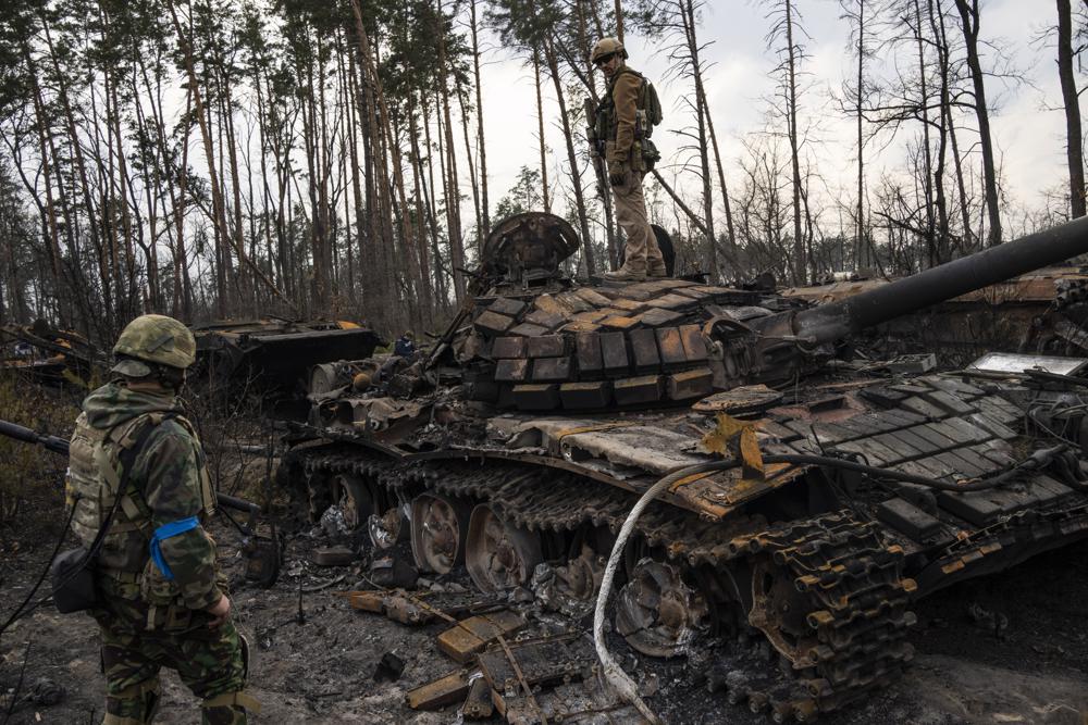 A Ukrainian soldier stands on top of a destroyed Russian tank on the outskirts of Kyiv, Ukraine, Thursday. Russian troops began leaving the Chernobyl nuclear plant after soldiers got “significant doses” of radiation from digging trenches at the highly contaminated site, Ukraine said. 