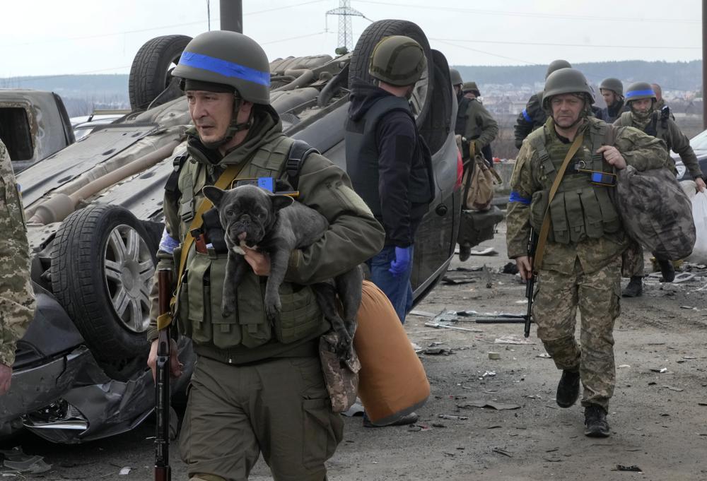 A Ukrainian soldier carries a dog saved from under the ruins of houses destroyed by the Russian forces in Irpin close to Kyiv, Ukraine, Thursday.