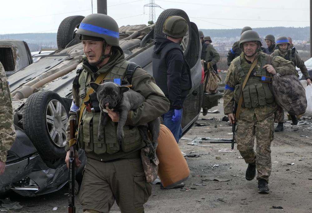 A Ukrainian soldier carries a dog saved from under the ruins of houses destroyed by the Russian forces in Irpin close to Kyiv, Ukraine, Thursday.