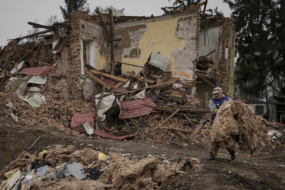 A man carries debris from buildings destroyed during fighting between Russian and Ukrainian forces outside Kyiv, Ukraine, Friday. Emergency relief and evacuation convoys for the besieged Ukrainian city of Mariupol remained in doubt Friday following reports of Russian interference, while Russian officials accused Ukraine of flying helicopter gunships across a border between the two countries and striking an oil depot.