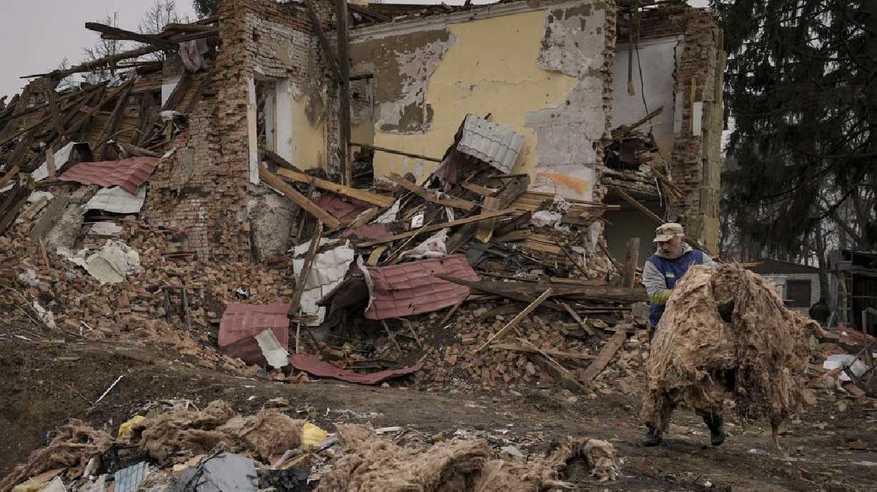 A man carries debris from buildings destroyed during fighting between Russian and Ukrainian forces outside Kyiv, Ukraine, Friday. Emergency relief and evacuation convoys for the besieged Ukrainian city of Mariupol remained in doubt Friday following reports of Russian interference, while Russian officials accused Ukraine of flying helicopter gunships across a border between the two countries and striking an oil depot.